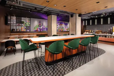 a bar in a restaurant with green chairs at Hyatt Place Krakow in Kraków