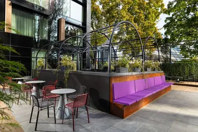 a purple bench in front of a building with tables and chairs at Hyatt Place Krakow in Kraków