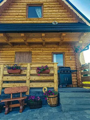 a wooden cabin with potted plants and a bench at Domki Na Grapie - z widokiem na Tatry in PyzÃ³wka