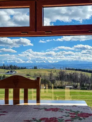a window in a room with a view of a field at Domki Na Grapie - z widokiem na Tatry in PyzÃ³wka