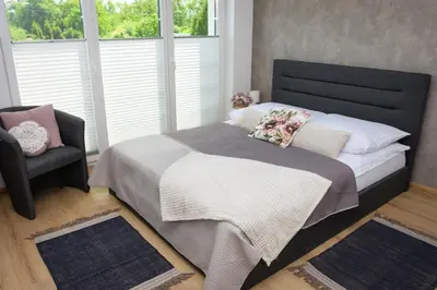 a bedroom with a bed with a chair and a window at Apartamenty Legionów 30 in Oświęcim