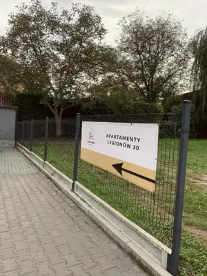 a sign on a fence in a park at Apartamenty Legionów 30 in Oświęcim