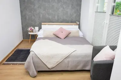 a bedroom with a bed with a pink pillow at Apartamenty Legionów 30 in Oświęcim
