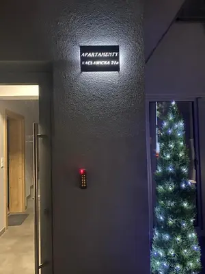 a christmas tree in a hallway with a sign at Apartamenty in Miechów