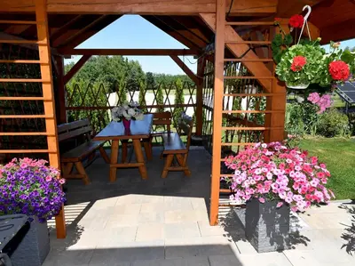a wooden gazebo with a table and flowers at Domek pod Zatorem in Ryczów
