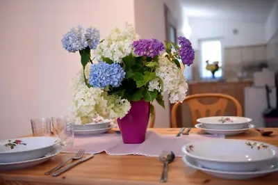 a table with a vase filled with purple and white flowers at Domek pod Zatorem in Ryczów