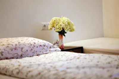 a vase of flowers on a table next to a bed at Domek pod Zatorem in Ryczów
