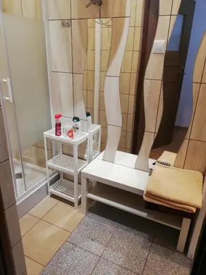 a shower with a white bench in a bathroom at Domek pod Zatorem in Ryczów
