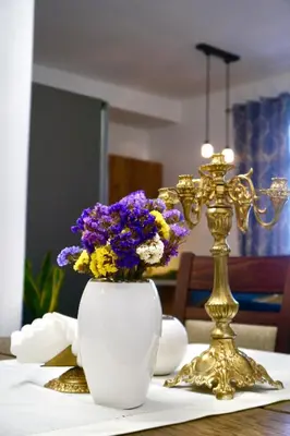 a table with a vase of flowers and a gold candlesticks at Goldengreen Apartment in Kraków