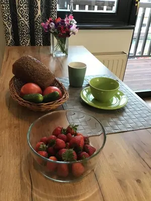 a bowl of strawberries and a basket of fruit on a table at Goldengreen Apartment in Kraków
