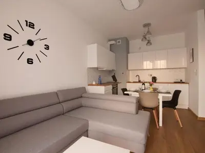 a living room with a couch and a clock on the wall at Apartamenty Vulcan in Zator