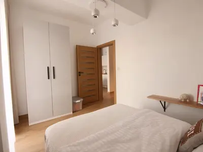 a white bedroom with a bed and a closet at Apartamenty Vulcan in Zator