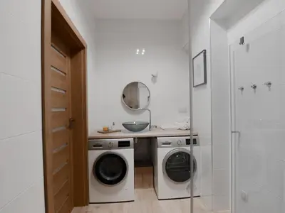 a white laundry room with a washer and dryer at Apartamenty Vulcan in Zator