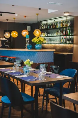 a dining room with tables and chairs and a bar at Hotel Perła in Kraków