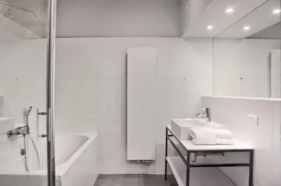 a white bathroom with a sink and a bath tub at Hotel Perła in Kraków