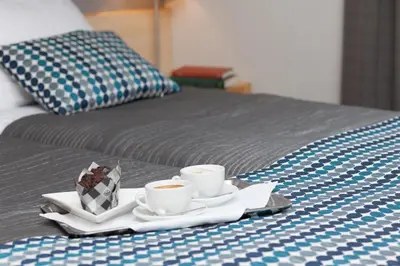 a tray with two cups of coffee on a bed at Hotel Perła in Kraków