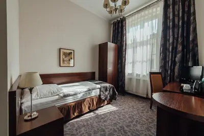 a bedroom with a bed and a desk and a window at Hotel Rezydent in Kraków