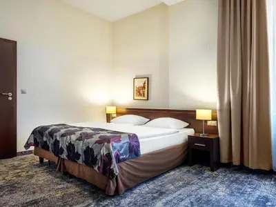 a hotel room with a large bed and two lamps at Hotel Rezydent in Kraków