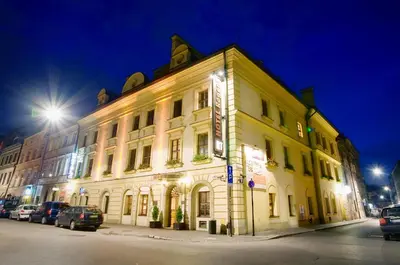 a large white building on a street at night at Hotel Regent in Kraków