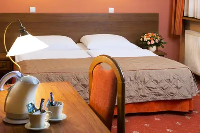 a hotel room with a bed and a wooden table at Hotel Regent in Kraków