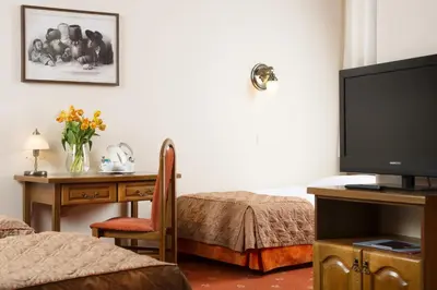 a hotel room with a tv and a desk with a desk at Hotel Regent in Kraków