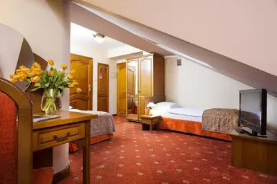 a hotel room with two beds and a television at Hotel Regent in Kraków