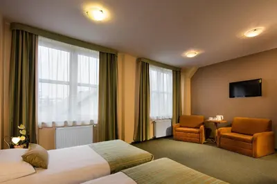 a hotel room with two beds and a chair at Hotel Galicya in Kraków