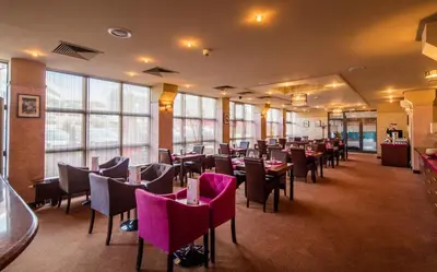 a dining room with tables and chairs and windows at Hotel Galicya in Kraków