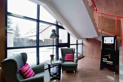 a room with two chairs and a table and windows at Hotel Galicya in Kraków