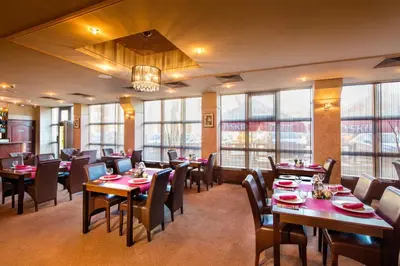 a restaurant with tables and chairs and windows at Hotel Galicya in Kraków