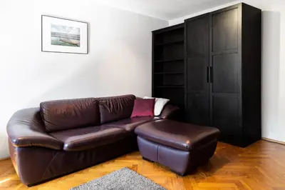 a living room with a brown leather couch and a stool at 2 Bedroom Apartment, Heart of Krakow Tomasza st in Kraków
