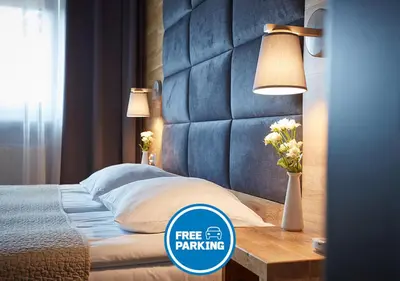 a bedroom with a bed and a table with a lamp at Hotel Batory in Kraków