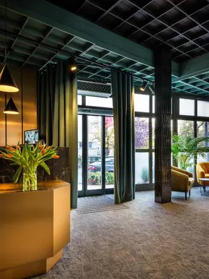 a lobby with large windows and a table at Hotel Batory in Kraków