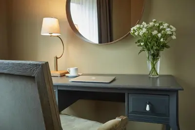 a desk with a vase of flowers and a mirror at Hotel Batory in Kraków