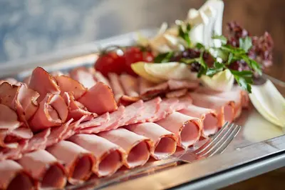a plate of ham and vegetables on a table at Hotel Batory in Kraków