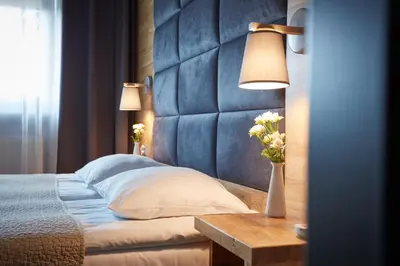 a bedroom with a bed with a blue headboard and a table at Hotel Batory in Kraków