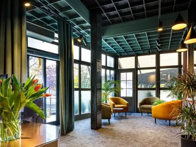 a lobby with yellow chairs and windows at Hotel Batory in Kraków