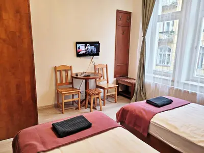 a room with two beds and a table and a tv at DReAM Post Aparthotel in Kraków