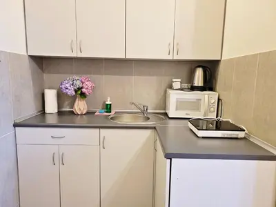 a kitchen with white cabinets and a sink and a microwave at DReAM Post Aparthotel in Kraków
