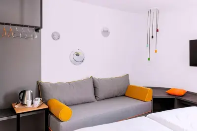 a living room with a couch with orange cushions at Vienna House Easy by Wyndham Cracow in Kraków