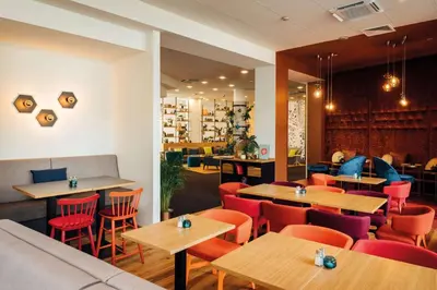 a restaurant with wooden tables and red chairs at Vienna House Easy by Wyndham Cracow in Kraków