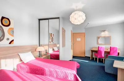 a hotel room with two beds and a desk at Hotel Petrus in Kraków
