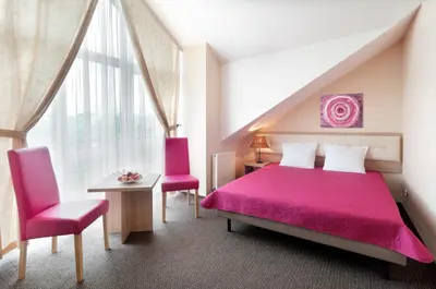 a bedroom with a pink bed and two pink chairs at Hotel Petrus in Kraków