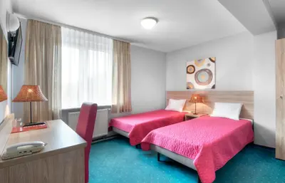 a hotel room with two beds and a desk at Hotel Petrus in Kraków
