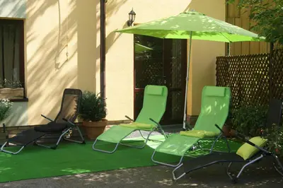 two green chairs and an umbrella on a patio at Hotel Petrus in Kraków