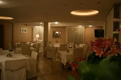 a restaurant with white tables and chairs and flowers at Hotel Petrus in Kraków