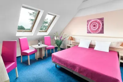 a bedroom with a pink bed and pink chairs at Hotel Petrus in Kraków