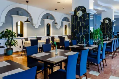 a dining room with tables and blue chairs at Hotel Wyspiański in Kraków
