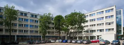 a large white building with cars parked in a parking lot at Hotel Wyspiański in Kraków