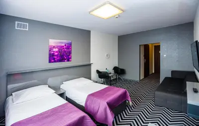 a hotel room with two beds and a tv at Hotel Wyspiański in Kraków
